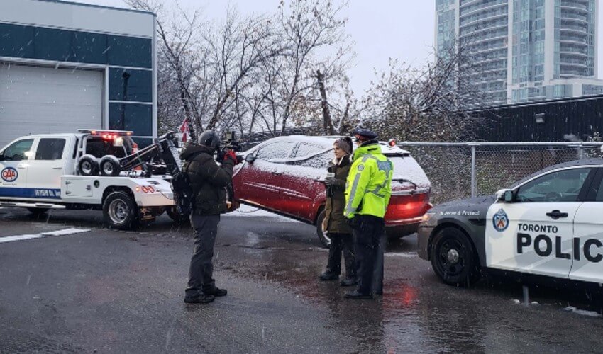 Tow truck, car and cruiser at collision reporting centre.