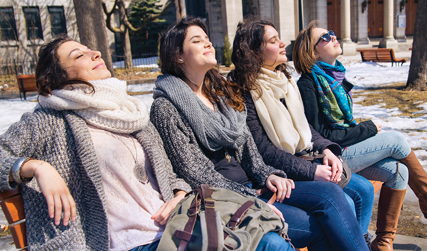 Four women enjoying the spring sunshine on a park bench.