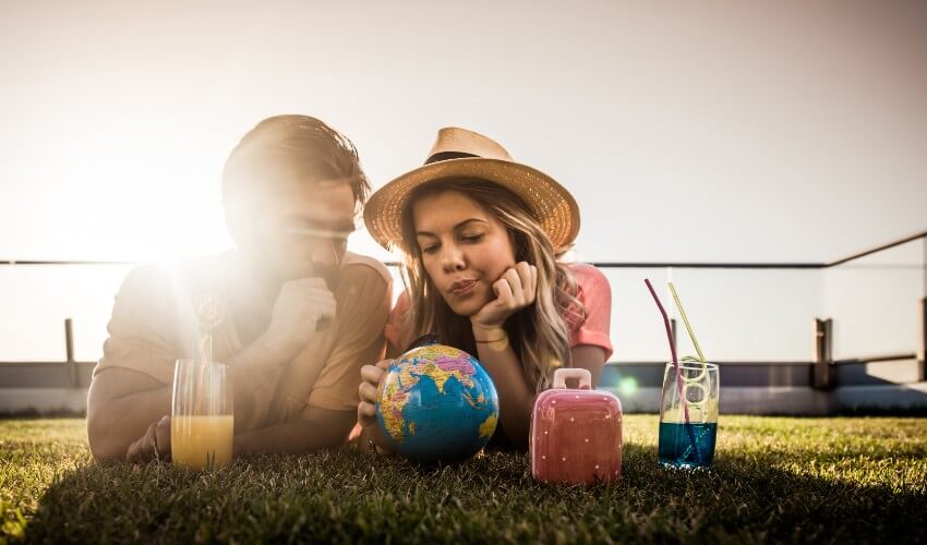 Young couple lying on the grass looking at a small world globe.