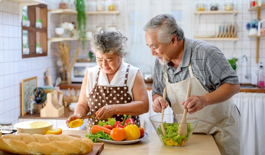 Mature couple cooking at kitchen counter.