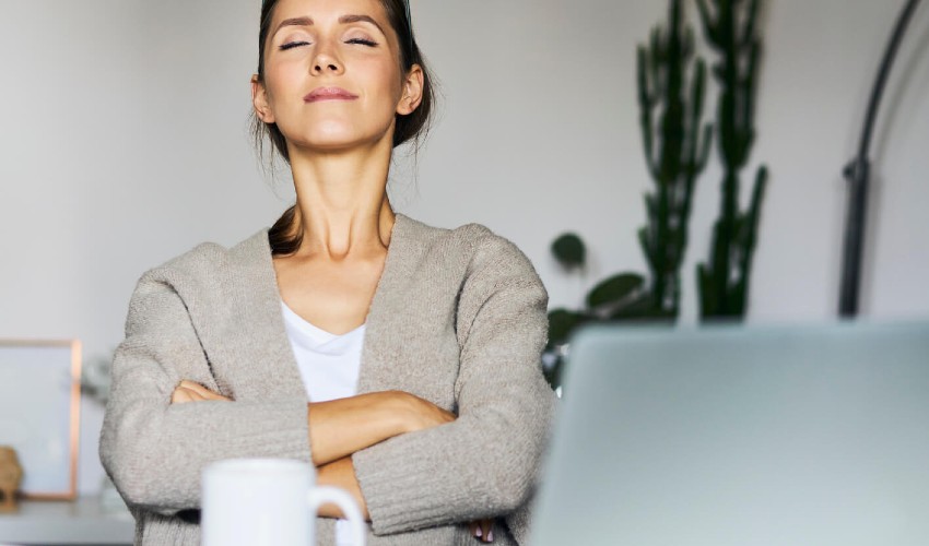 Woman at her desk, taking a break and sitting in front of her laptop.