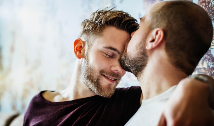 Man kissing his partner on the forehead.