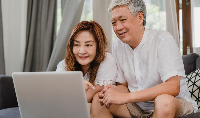 Mature couple on couch looking at laptop 