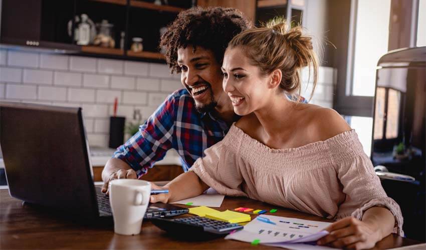 Young couple seated in front of a laptop working on their finances. 