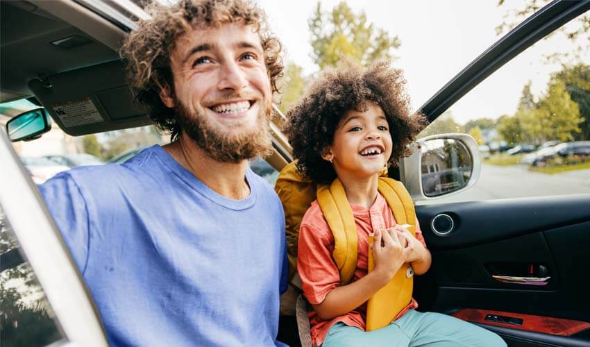 Young dad and toddler in car with open door