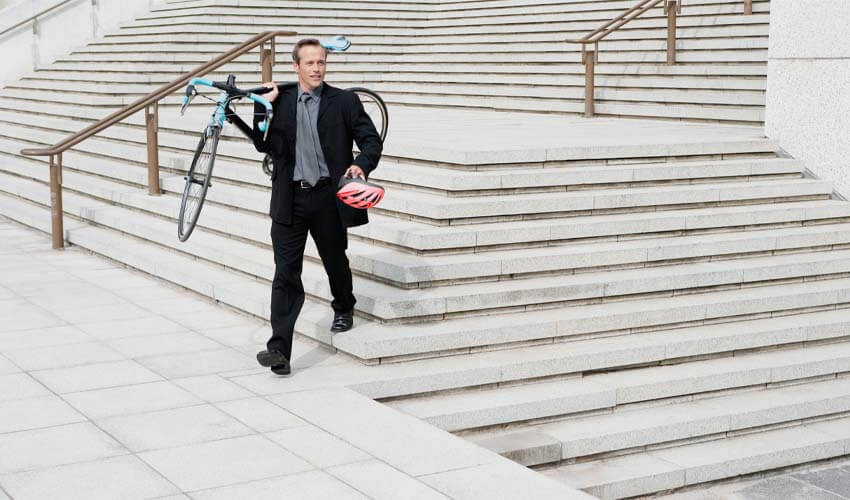 Businessman carrying bike and helmet down stairs