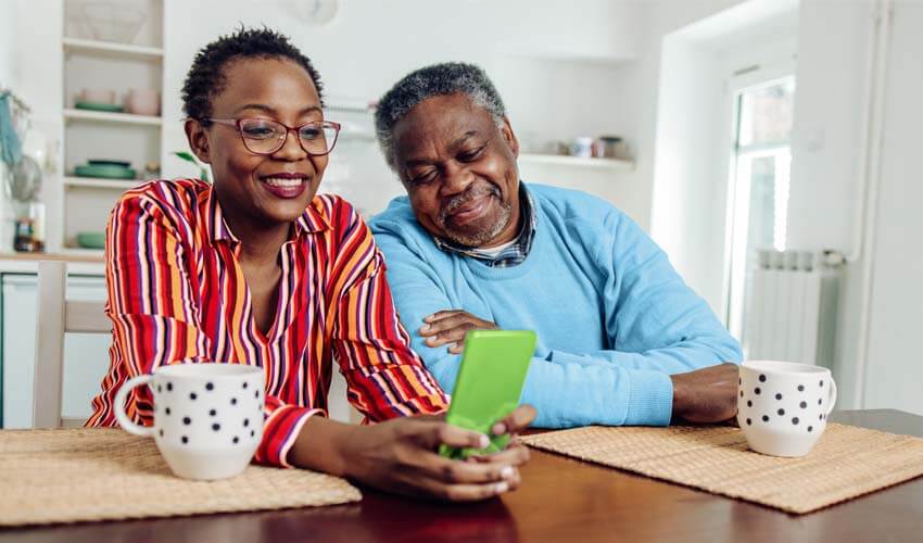Mature couple with smartphone in kitchen