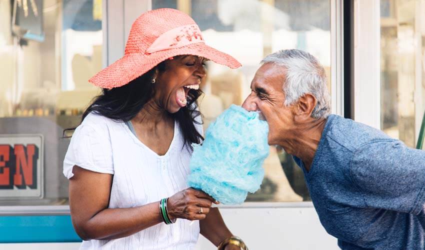 Senior couple laughing and eating cotton candy in Long Beach, California, USA