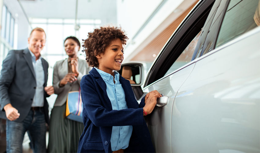 Family of three looking at new car inside car dealership