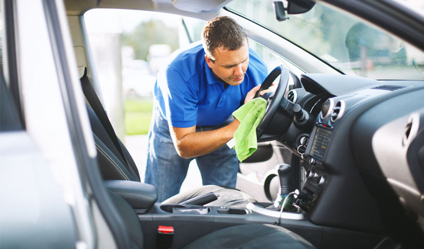 Man wiping down steering wheel in car