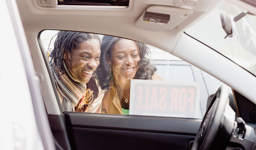 Young couple looking inside car for sale