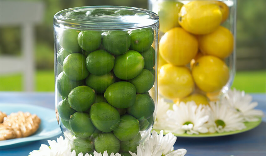 Glass bowls of lemons and limes surrounded by daisies.