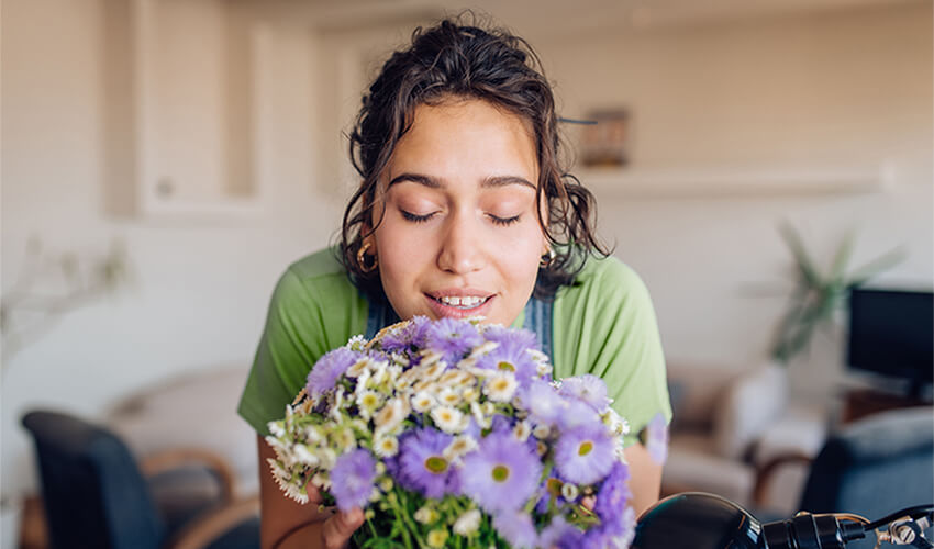 Woman smelling purple flowers.