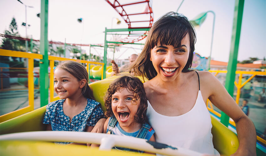 Mother on roller coaster with two young daughters.