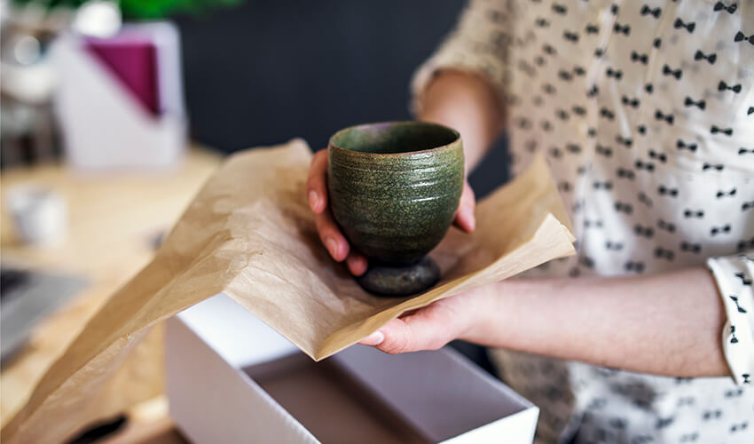 Wrapping up a dark green piece of pottery.