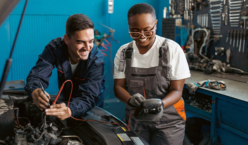 Male and female mechanics testing car battery