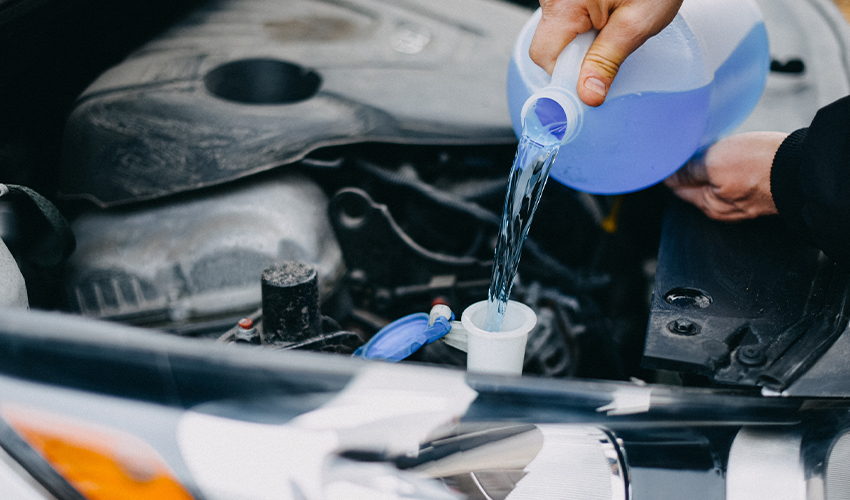 Pouring windshield washer fluid into car