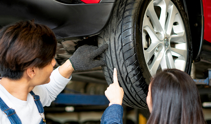 Mechanic showing woman tread on winter tires