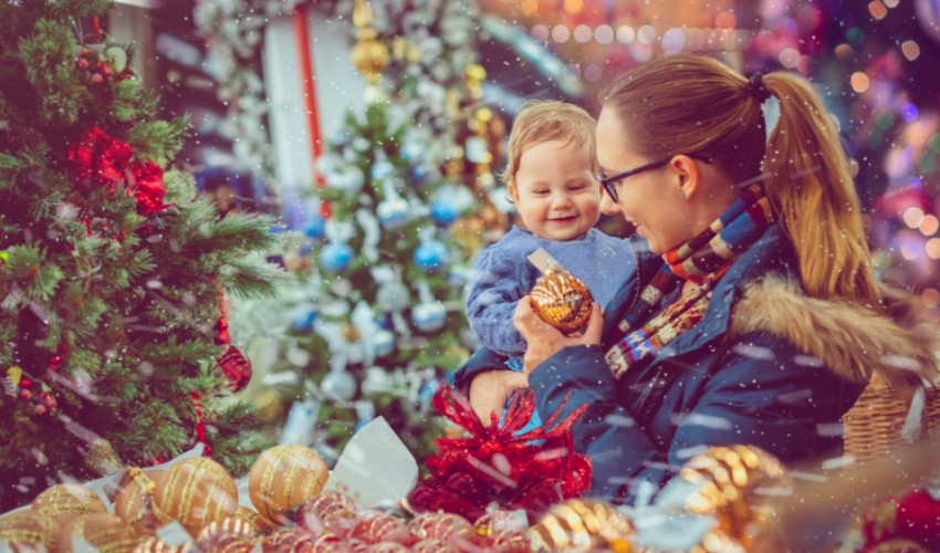 Mother and young child looking at ornaments at a holiday market.