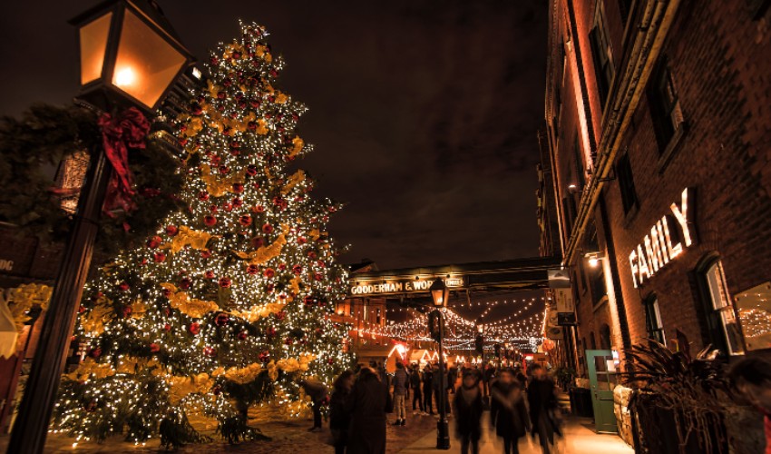 People walking around the Toronto Christmas Market in the Distillery District at night.