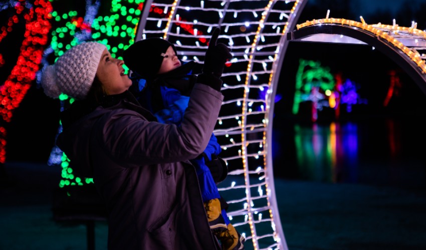 Mom carrying her young child looking light displays at the Winter Festival of Lights at Niagara Falls.