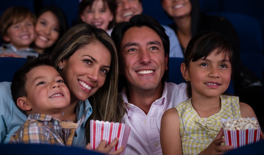 Family of four at the movies eating popcorn.