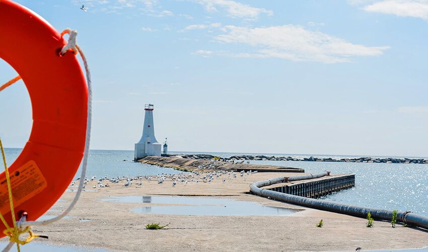 Waterfront harbor view of lighthouse and swimming safety ring at Cobourg beach, Ontario Canada.
