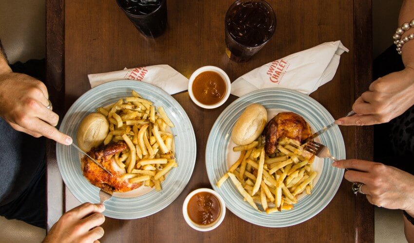 Two Swiss Chalet Quater Chicken Dinners on a table.