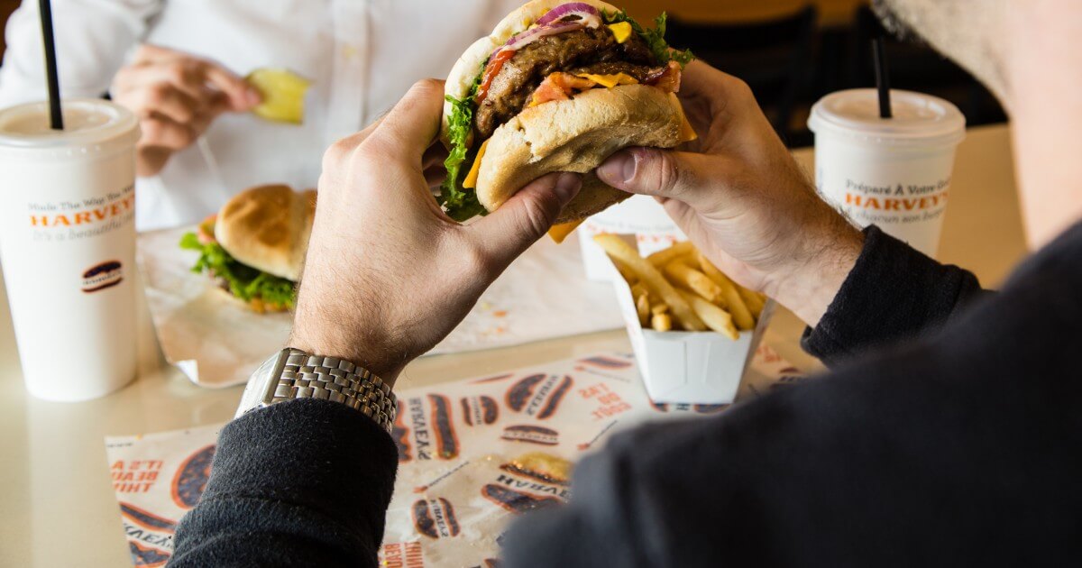 Man eating Harveys cheeseburger.