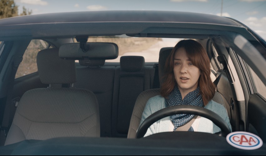 Female driver with CAA sticker on windshield.
