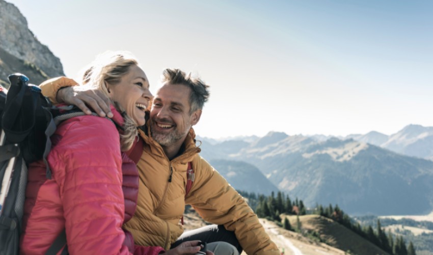 Happy couple sitting on Alaskan mountain side in winter.