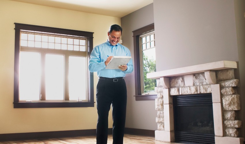 Male home inspector taking notes of the interior of a house.