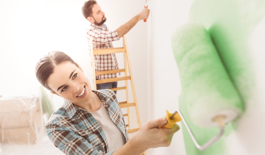 Happy couple painting walls in their new home.