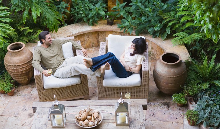 Couple seated on wicker chairs on an outdoor, designer inspired patio