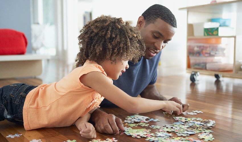 Dad and young daughter building a puzzle.