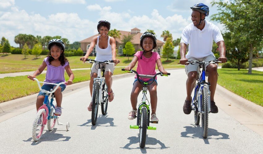 Parents and two young daughters biking on the road.