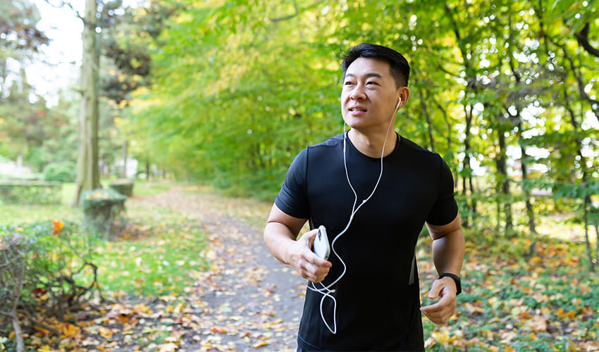 A man running in the beginning of the fall surrounded by trees.