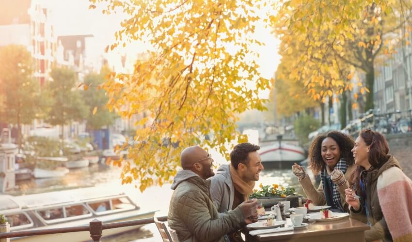  Two young couples dining by a canal in Amsterdam.