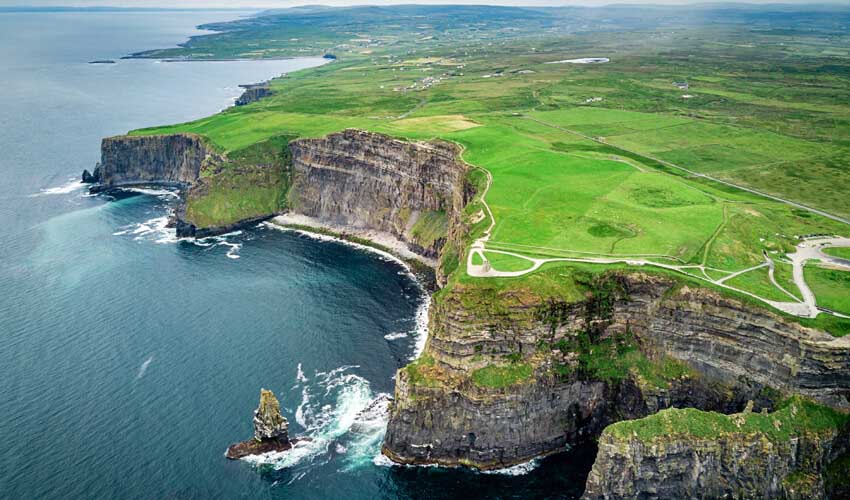 Drone’s view of the vibrant green atop Ireland’s Cliffs of Moher, with the navy waters of the Atlantic ocean below.