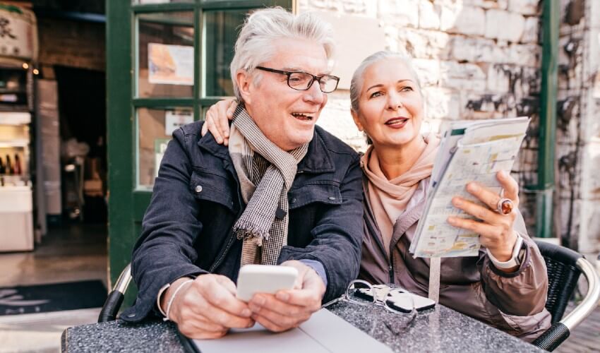 Mature couple looking at map at outdoor European café.
