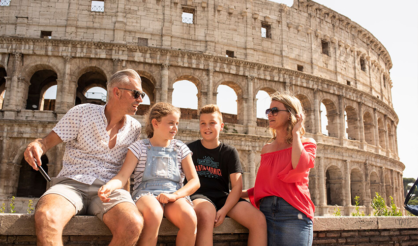 Family of four sitting in front of Colosseum