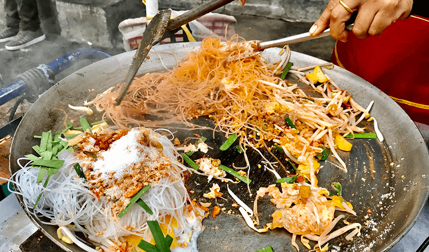 A person cooking outside Pad thai, or phad thai in Thailand.