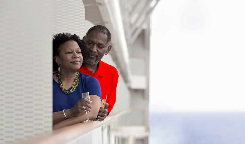 Couple standing at ocean cruise ship balcony.