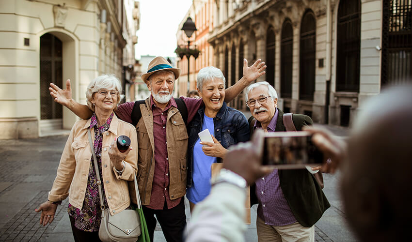 Mature travellers posing for photos in European street.