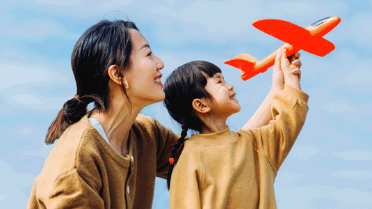 Image of a mom and daughter where the daughter is holding a paper airplane