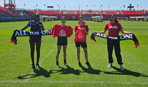 Four women in soccer field holding banners