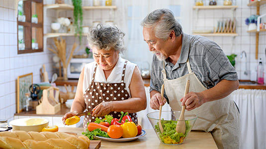 Mature couple cooking at kitchen counter