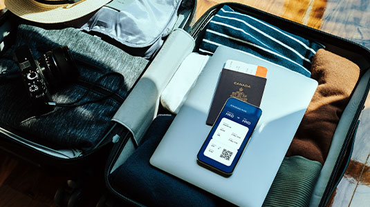 Inside a packed luggage with clothes, laptop, passport and a ticket