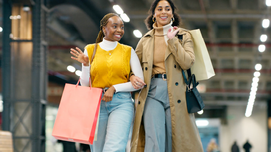 Couple of friends walking and holding shopping bags