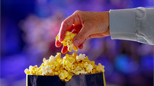 Person grabbing popcorn from a bag